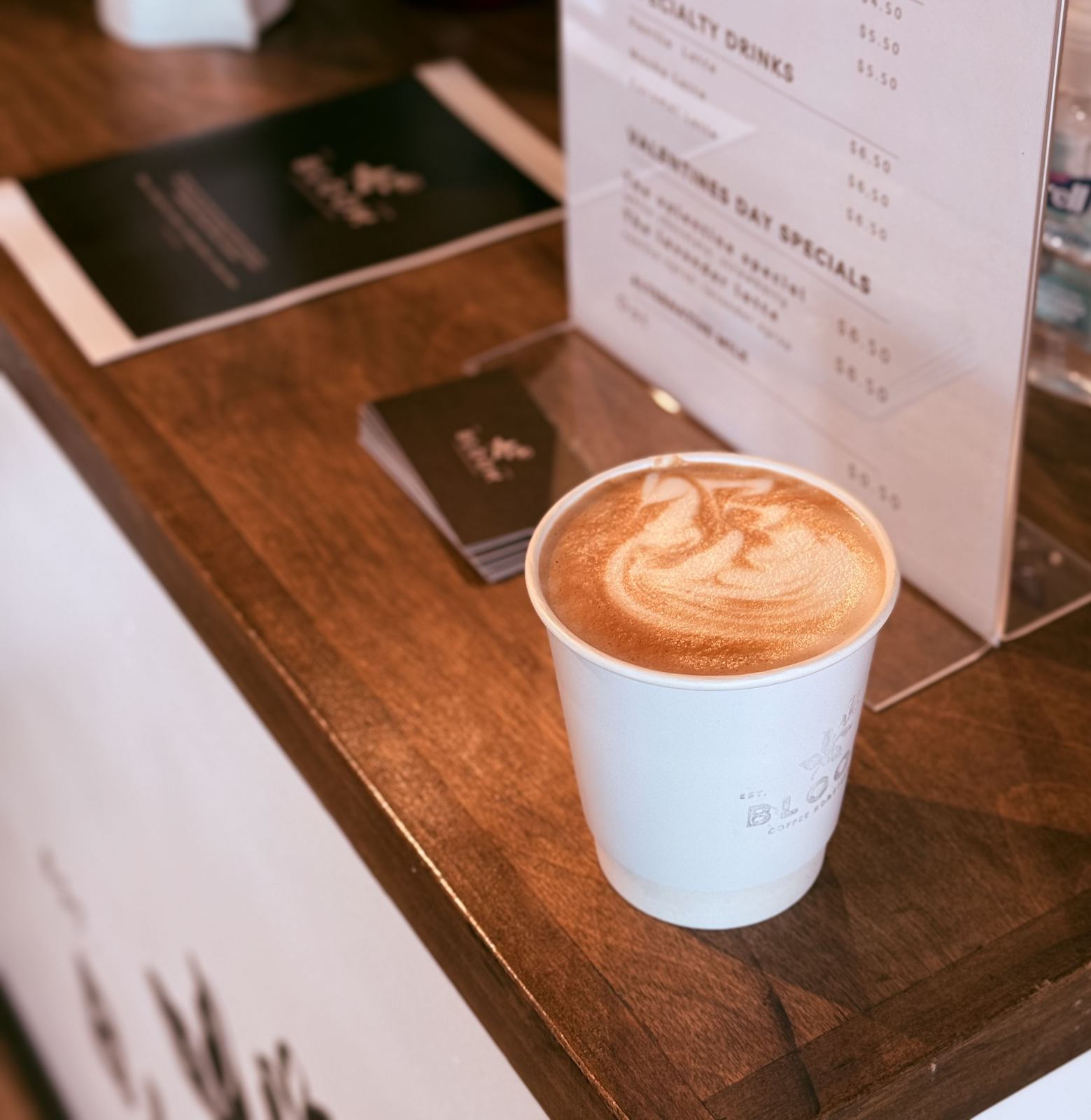 Latte beside the Bloom menu and business cards